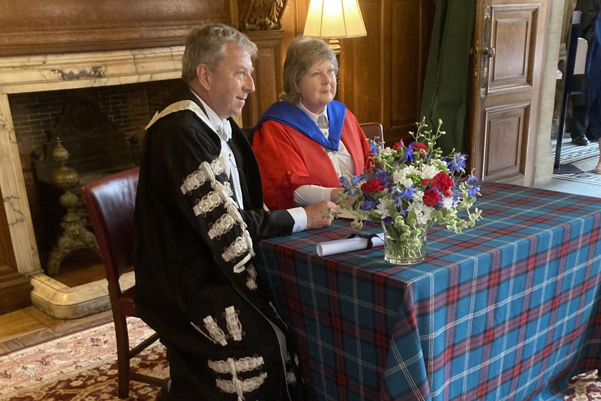 Professor Norma Dawson sitting at a table receiving her honorary degree