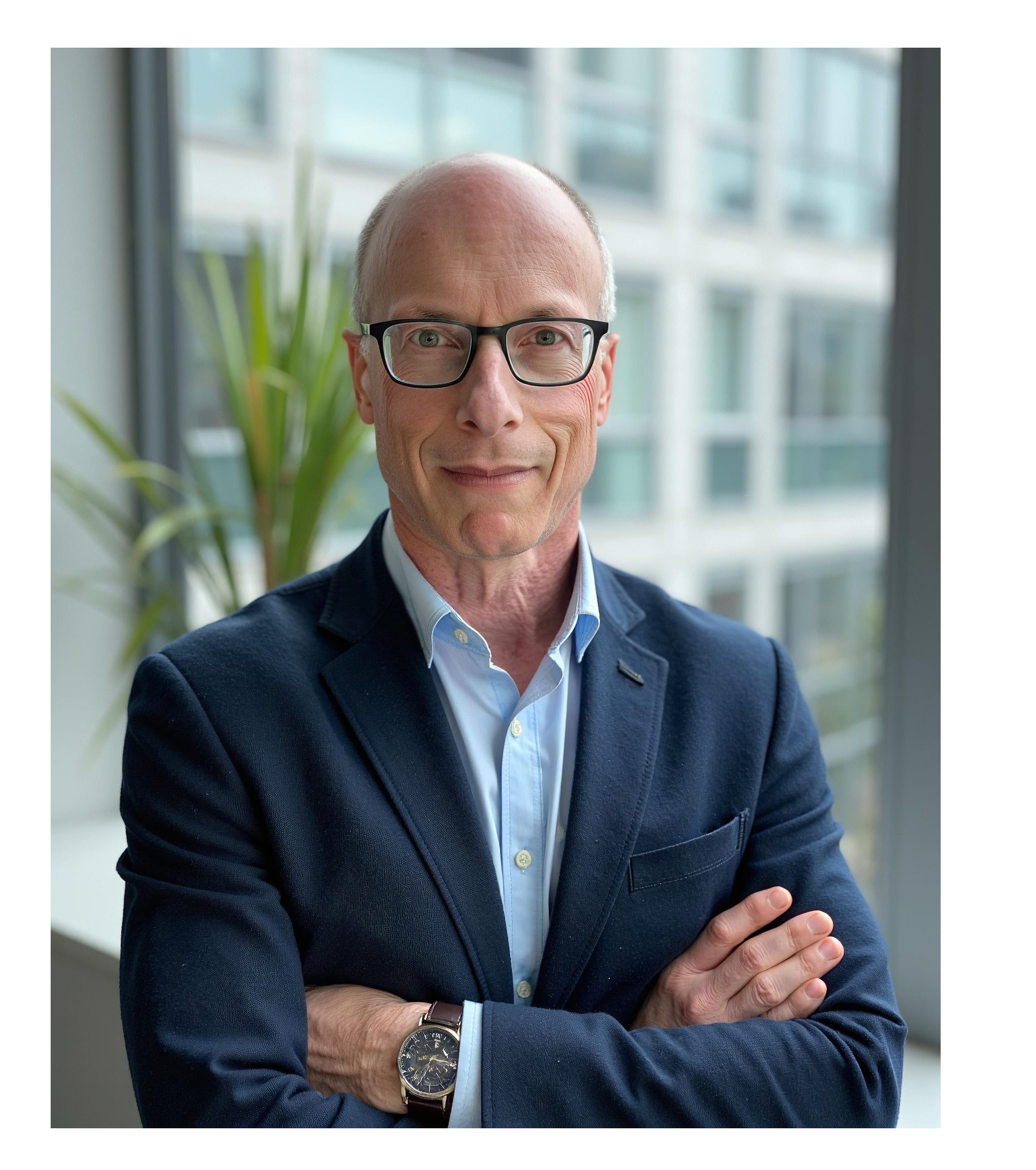 Joel P. Trachtman stands with his arms folded in front of a window. 