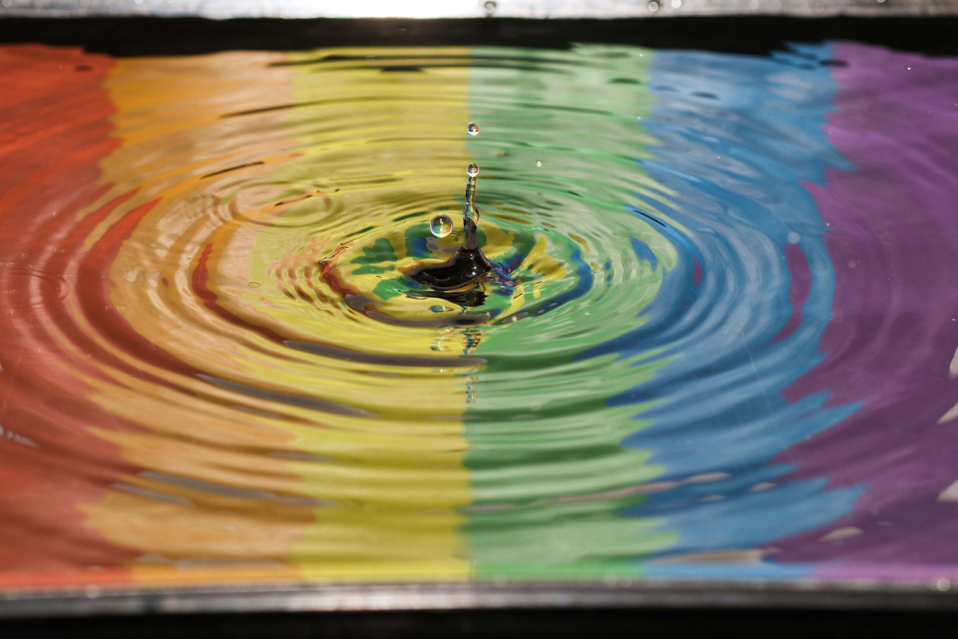 Water droplent in puddle with refletion of pride flag