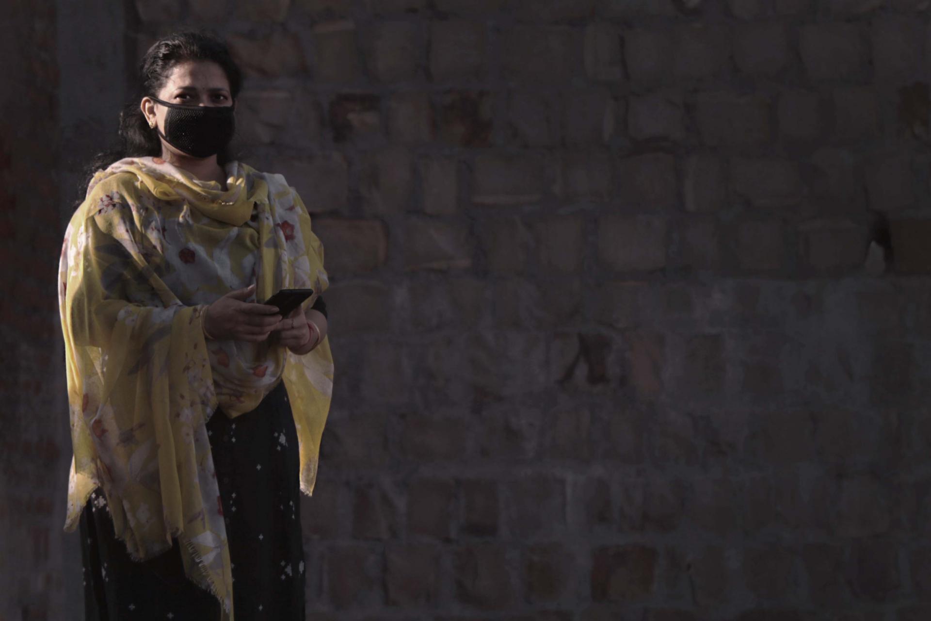 Woman in yellow sari with face mask 