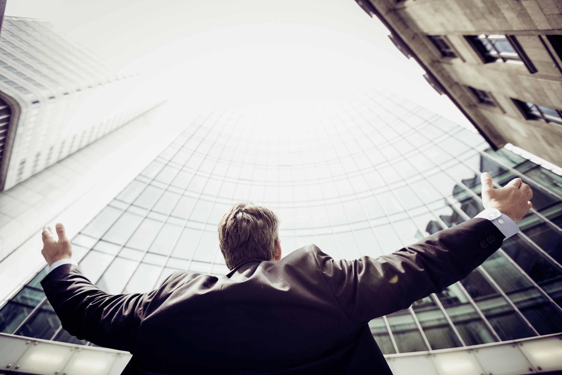 low angle shot of man in suit infront of glass building