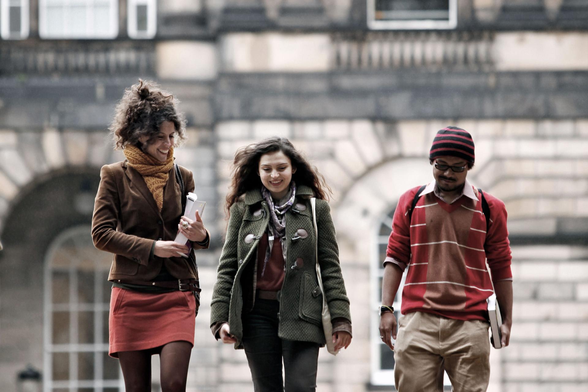 a group of three students walking together at Old College