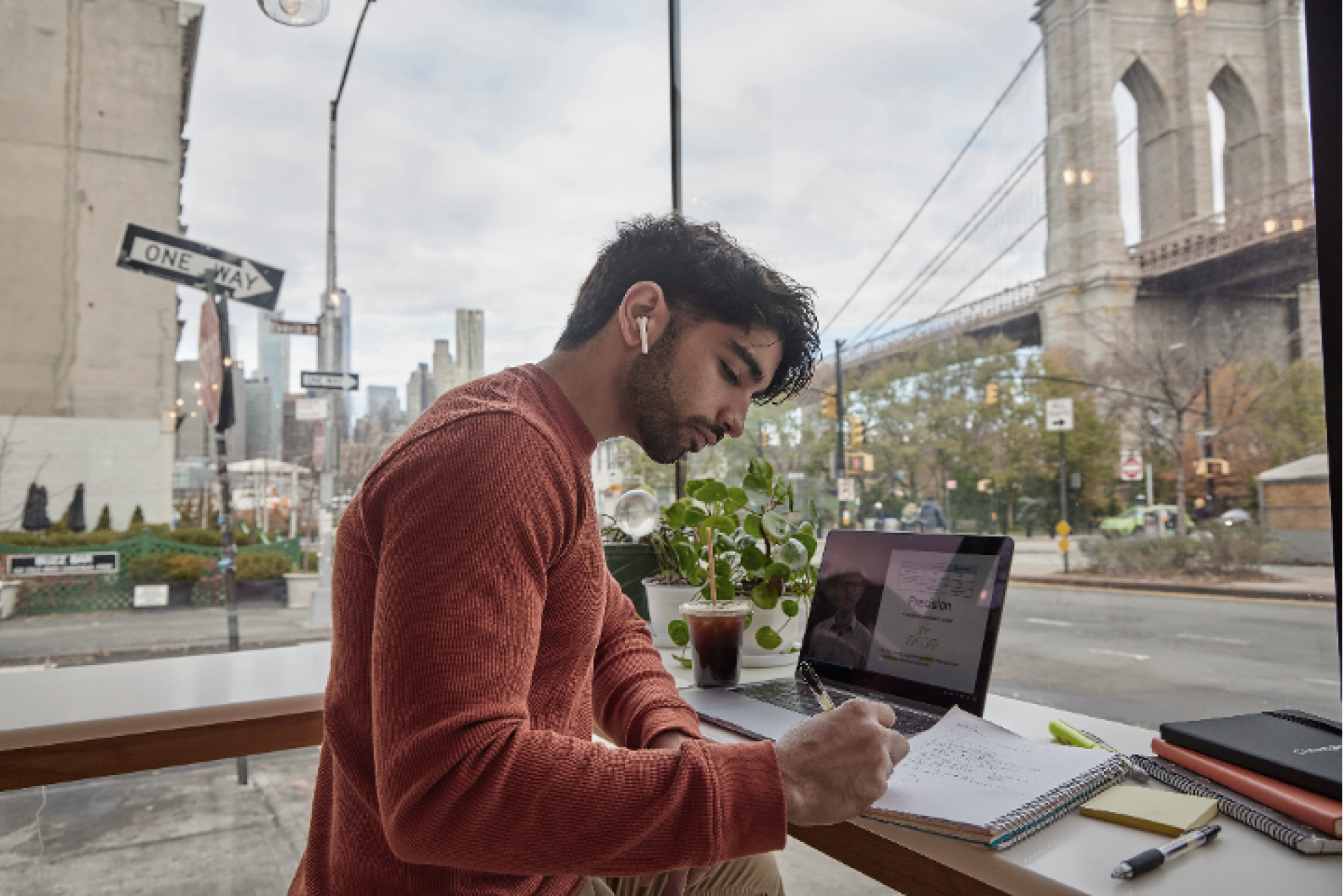 a man taking notes with a laptop in the background