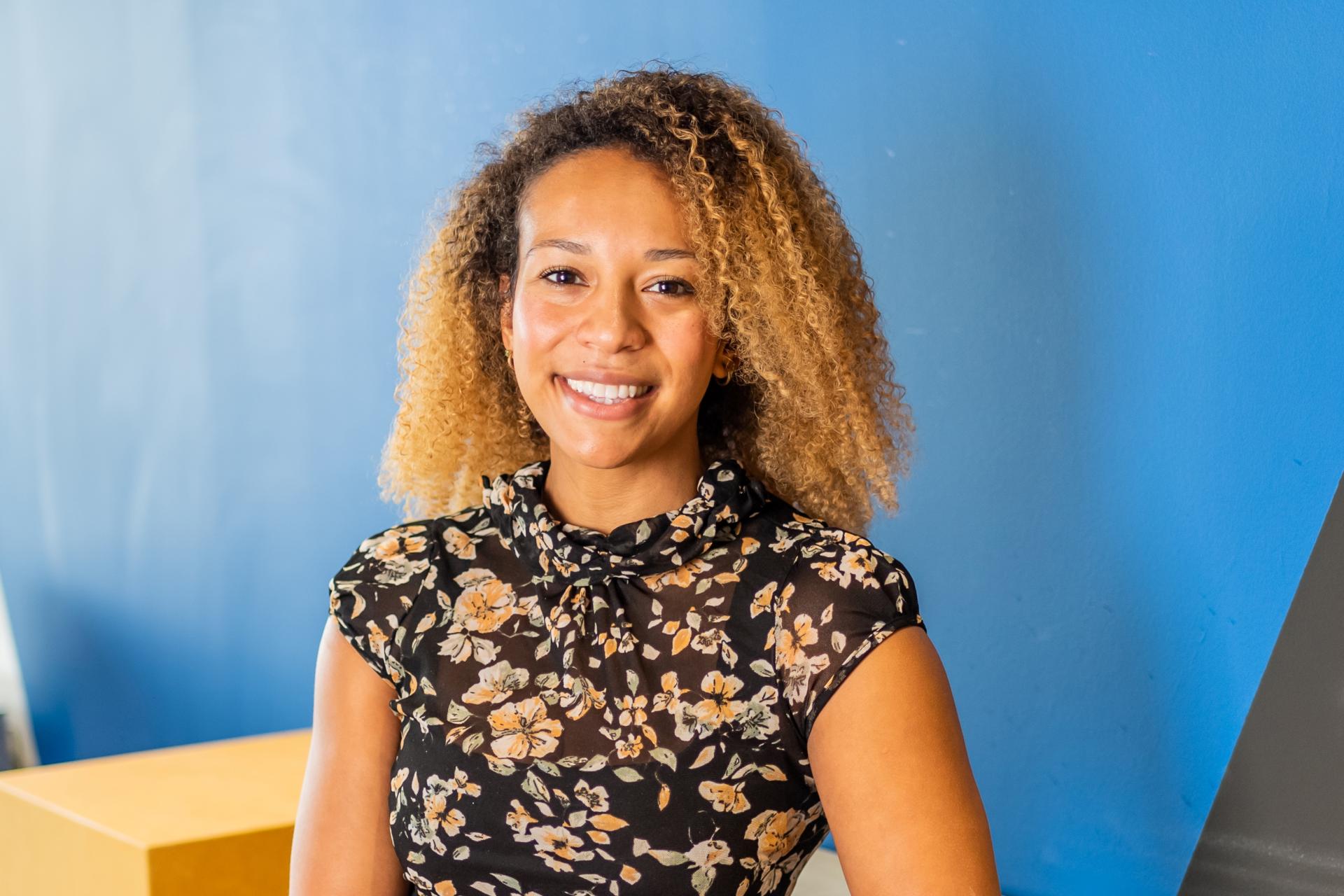 Jamila Archibald smiling in front of a blue wall