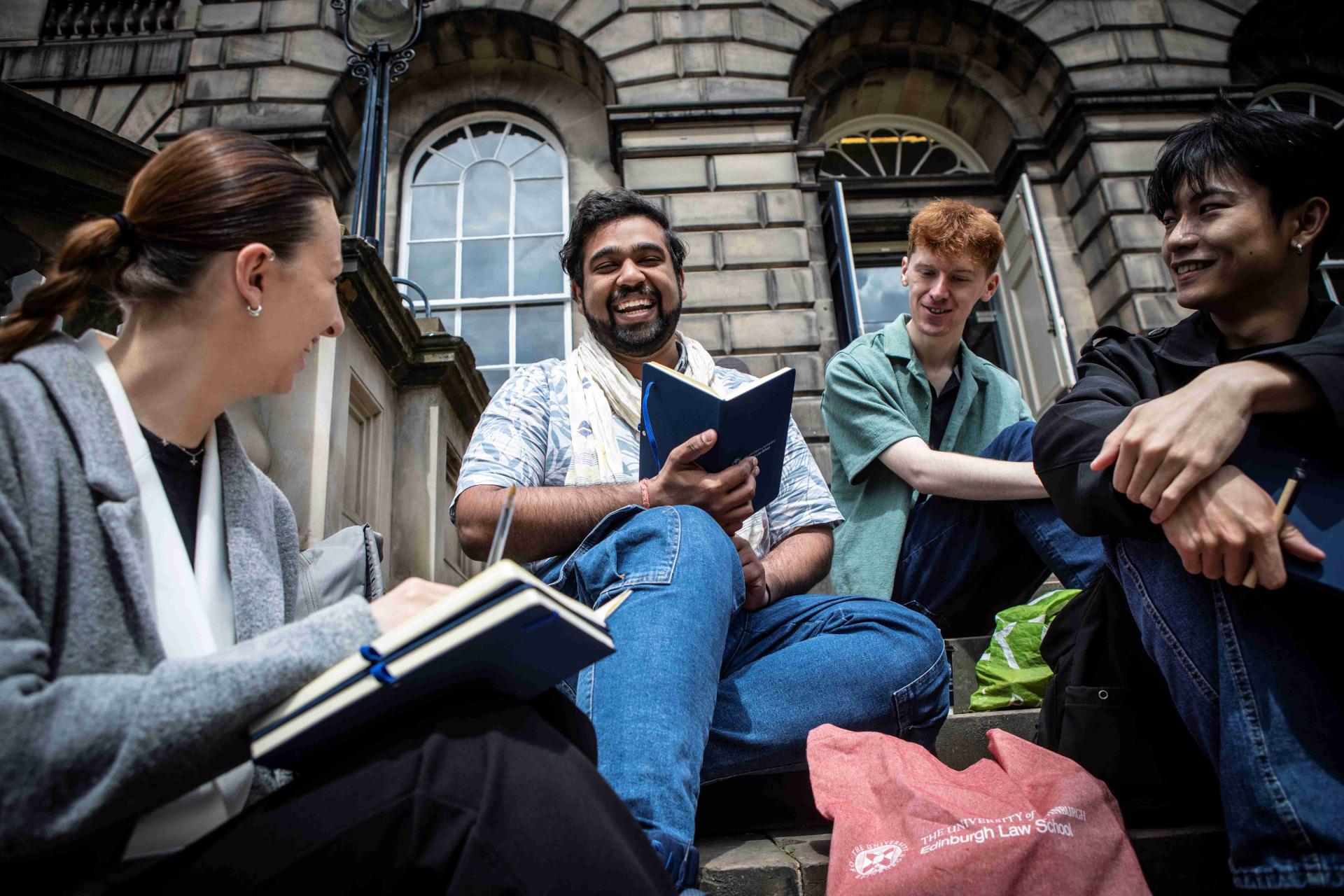 Students sitting on steps outside of Edinburgh Law School building