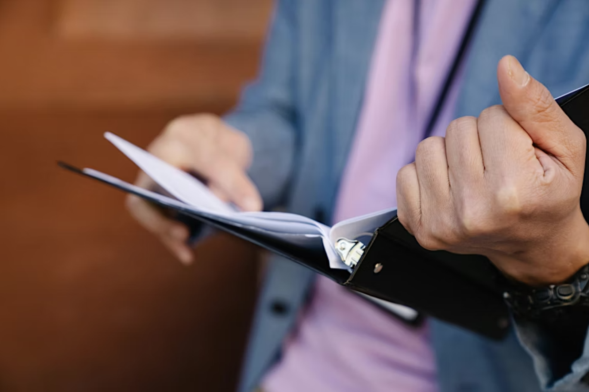 A person holds a binder folder, examining a sheet inside of it. 