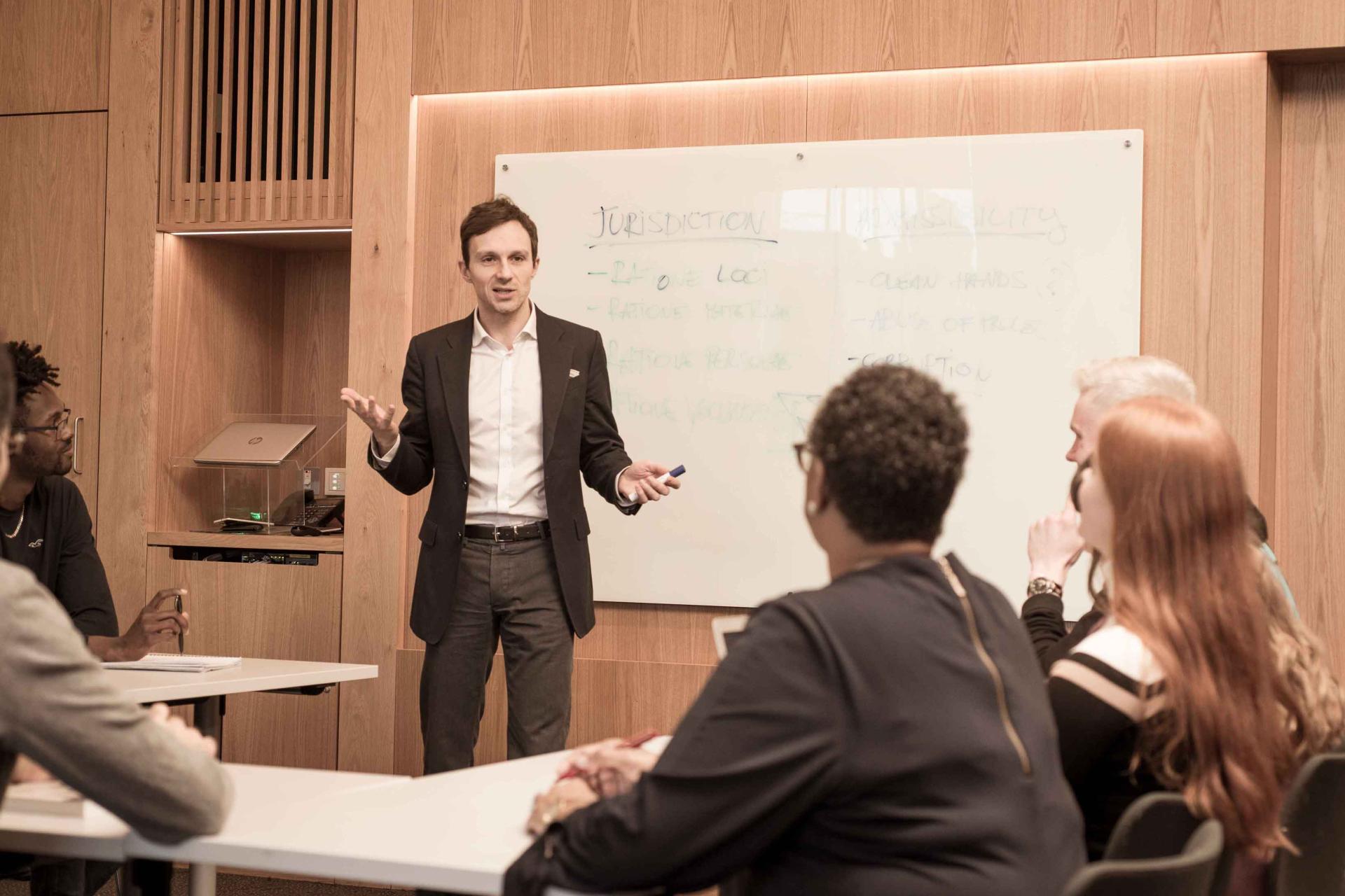 a man standing in front of a whiteboard talking