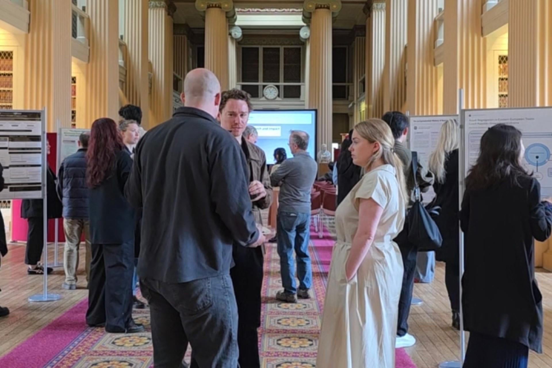 a group of people standing talking at the research and impact event