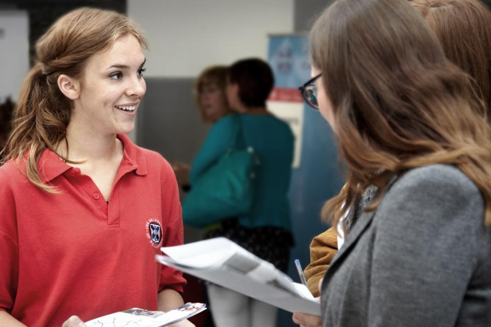 A University of Edinburgh student helper talks to prospective students
